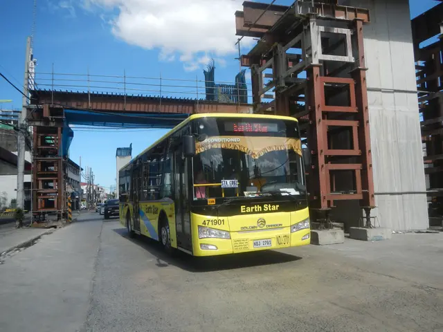 The image shows a yellow bus driving down a street next to a building under construction. On the...