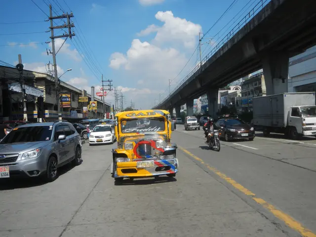 The image shows a yellow taxi driving down a street lined with tall buildings, electric poles with...