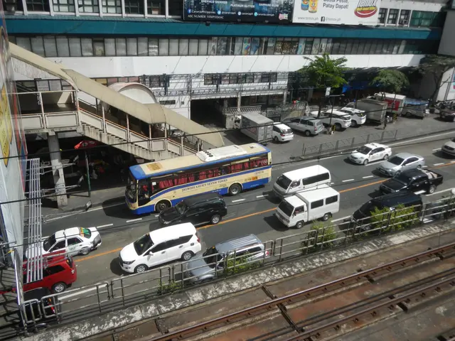 The image shows a bustling city street with cars and buses driving down it, surrounded by...