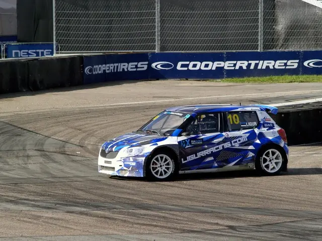 The image shows a blue and white car driving down a race track, with text and numbers on the car....