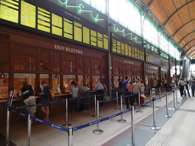 The image shows a group of people standing in line at a train station, with some of them wearing...