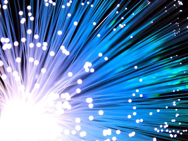 The image shows a close up of a fiber optic cable with blue and white lights against a black...
