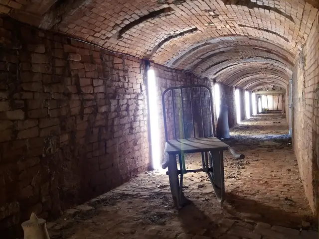 The image shows an old brick tunnel with a chair in the middle of it. The walls of the tunnel are...