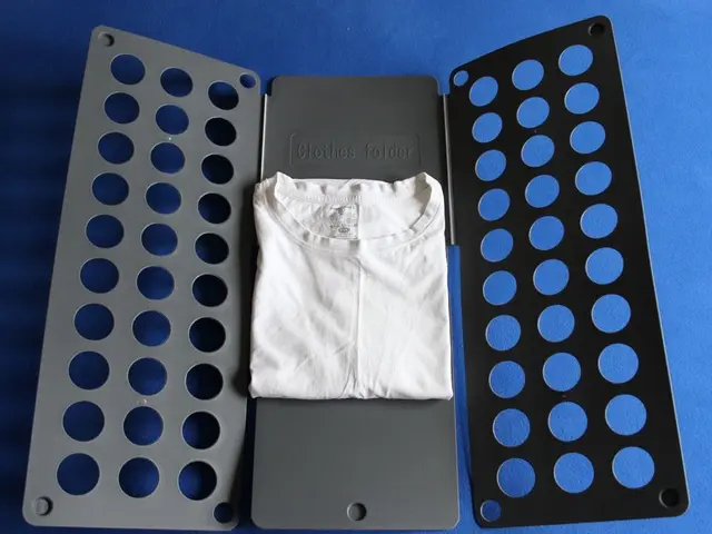 The image shows a white t-shirt sitting on top of a blue surface next to a black and ash colored...