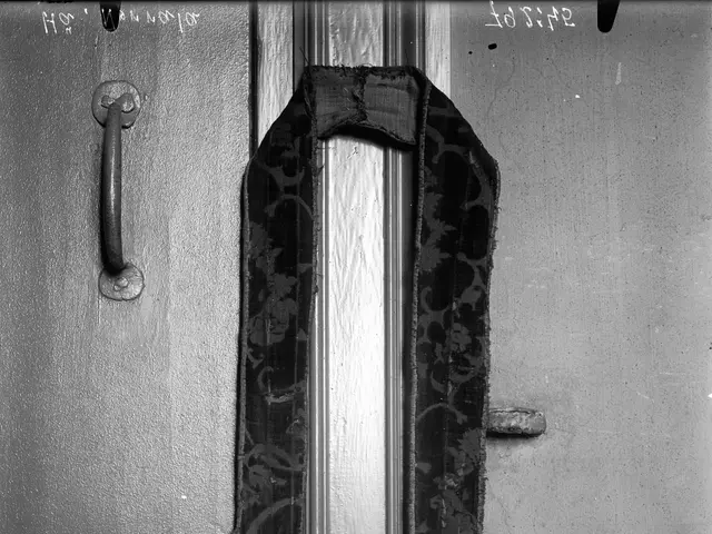 The image shows a black and white photo of a door with a handle and a cloth tied to it. The cloth...