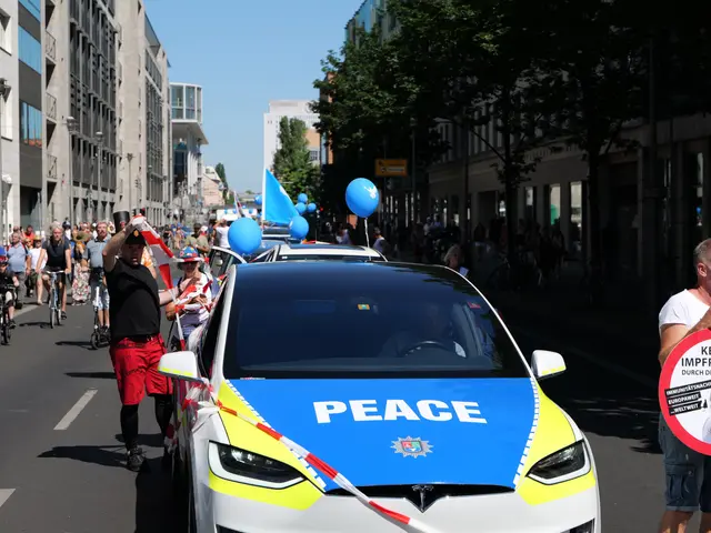 The image shows a group of people riding bicycles down a street, with a police car in the...