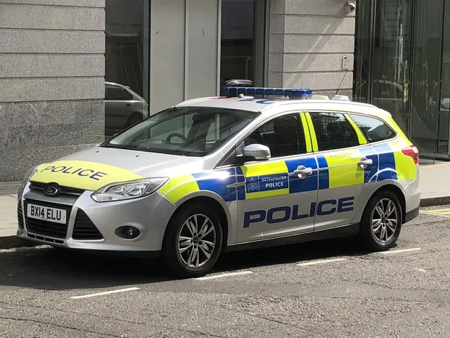 The image shows a police car parked on the side of the road in front of a building with glass...