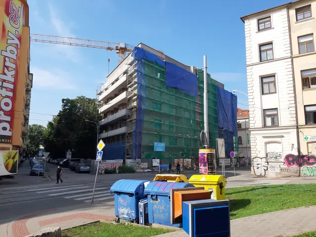 The image shows a bustling city street with a large building under construction in the background....