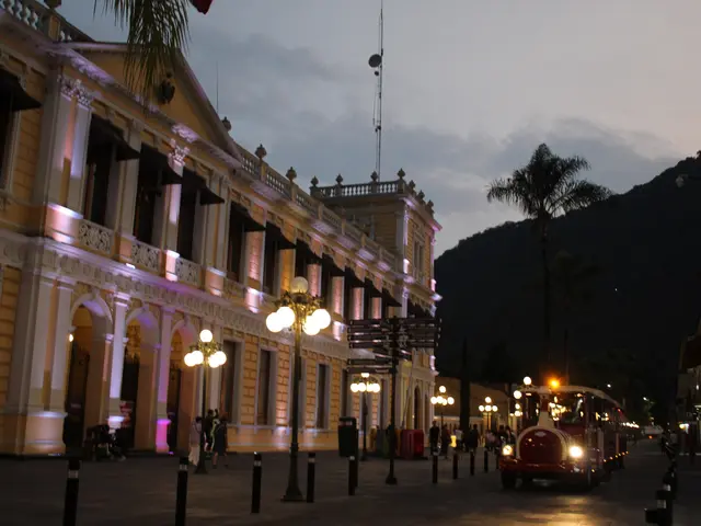 The image shows a city street at night with a building in the background. There are street lights...
