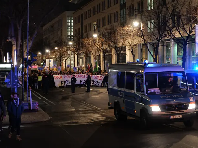 The image shows a group of people walking down a street at night, illuminated by street lights and...