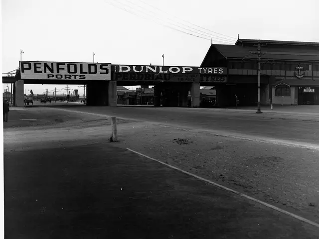 The image shows a black and white photo of Penfolds Dunlop Tyres, with a road in the foreground, a...
