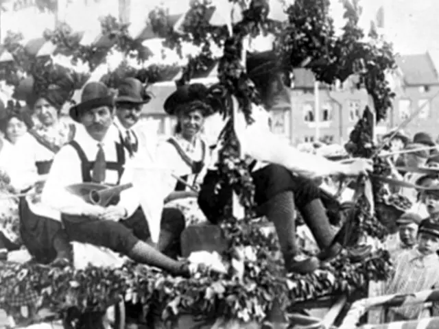 The image shows a group of people riding on top of a float in a parade. The people are wearing...
