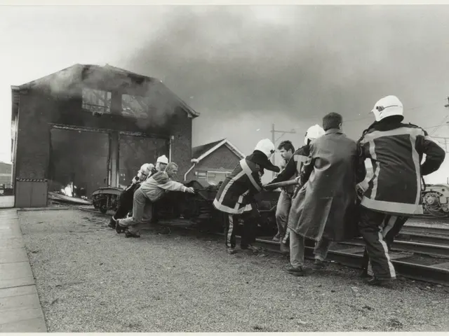 The image shows a group of people standing around a train on a track, with a house in the...