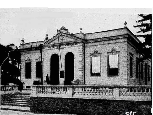 The image shows a black and white photo of a building with windows, doors, pillars, steps,...