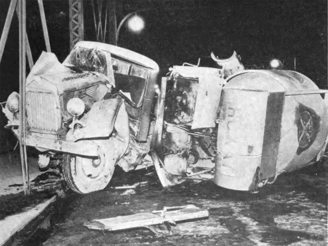 The image shows a black and white photo of a car that has been flipped over on the side of the...