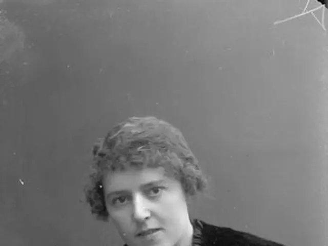 The image shows an old black and white photo of a woman wearing a fur stole. She has a serious...