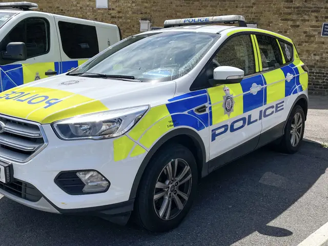 The image shows two police cars parked next to each other in a parking lot, with a wall in the...