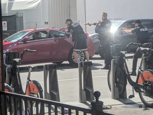 The image shows a group of police officers standing next to a red car in a parking lot. There are...