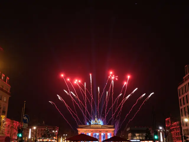The image shows a city street filled with lots of buildings, trees, light poles, traffic signals,...