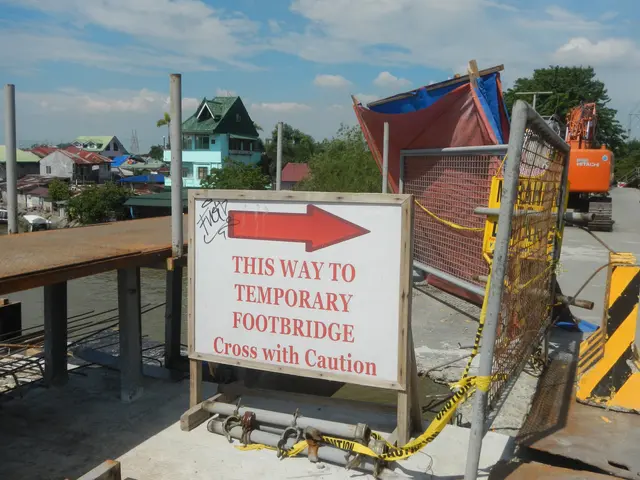 The image shows a temporary footbridge with a sign that reads "This Way to Temporary Footbridge...
