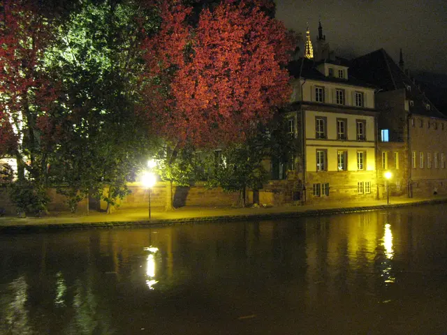 The image shows a river running through a city at night, illuminated by street lights and...