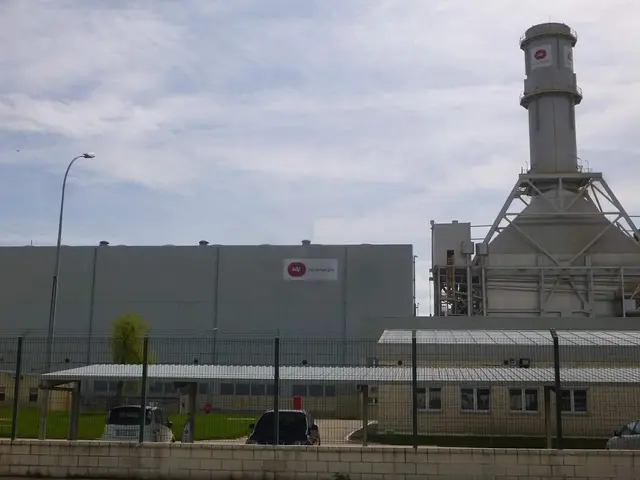 The image shows a large building with a tower in the middle of it, surrounded by a fence, with...