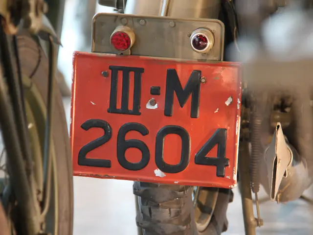 The image shows a close up of a motorcycle with a license plate on it. The license plate has text...