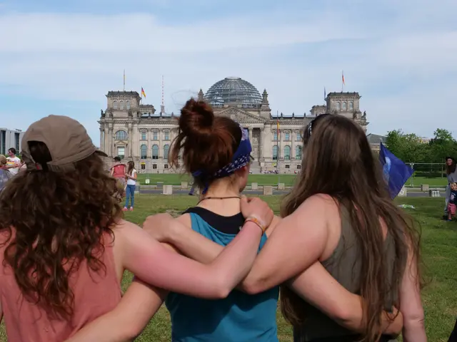 The image shows three women standing in front of the Reichstag building in Berlin, Germany. They...