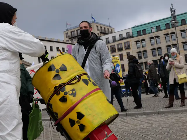 The image shows a man in a white suit carrying a yellow barrel with a radioactive symbol on it,...