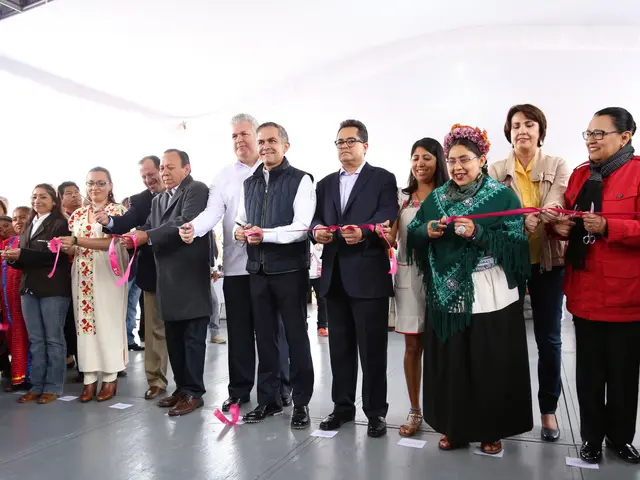The image shows a group of people standing in front of a crowd, smiling and holding a pair of...