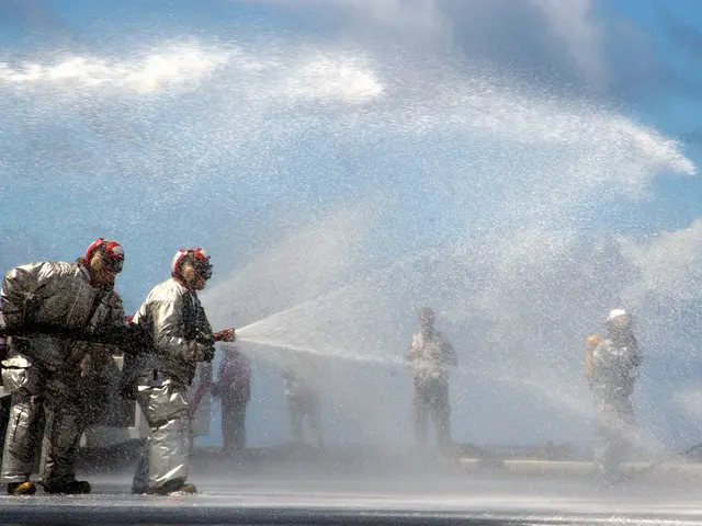 The image shows a group of firefighters wearing helmets and gloves, spraying water from a hose onto...
