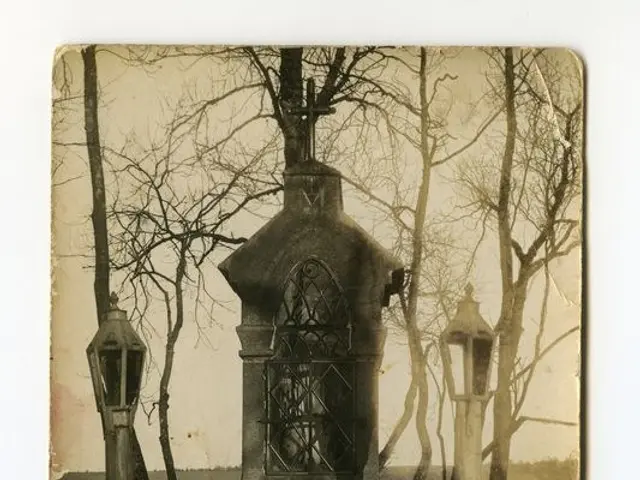 The image shows a black and white photo of a tombstone in the middle of a cemetery, surrounded by...