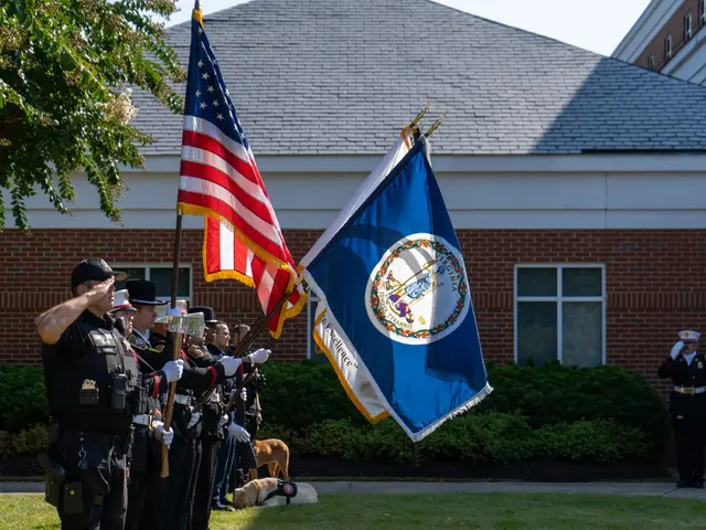 The image shows a group of police officers standing in front of a building, holding flags. They are...