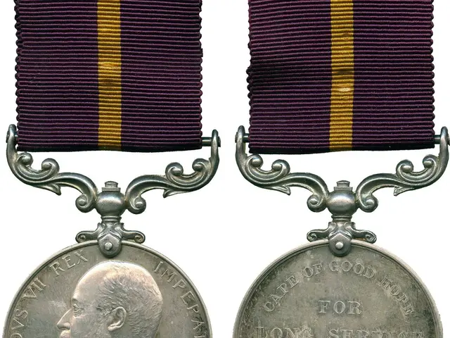 The image shows a silver medal with a purple and yellow ribbon attached to it. On the left side of...