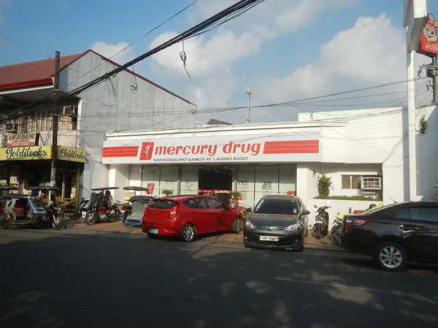 The image shows a bustling street with vehicles on the road, buildings with name boards, electric...