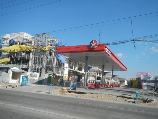 The image shows a gas station under construction on the side of a road, with buildings under...
