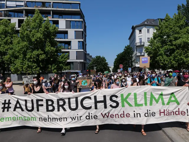 The image shows a group of people wearing masks and holding a banner that reads "Aufbruchsklima" in...