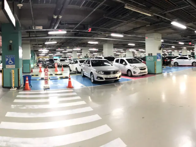 The image shows a parking garage filled with lots of cars parked in it, illuminated by lights on...