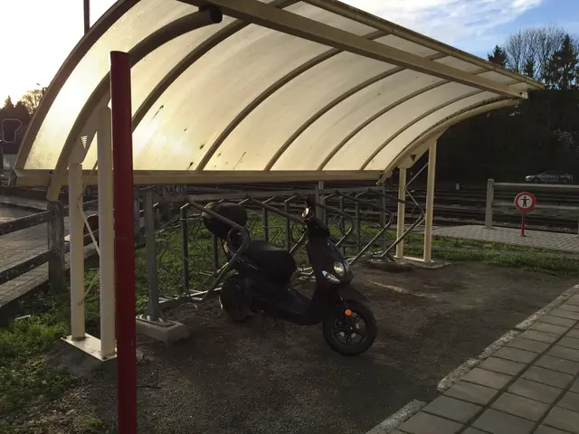The image shows a scooter parked under a canopy at a train station. The platform is surrounded by...