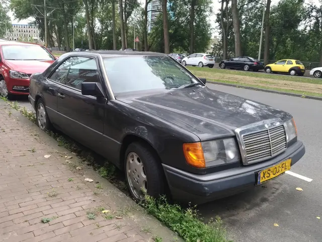 The image shows a black Mercedes-Benz E-Class parked on the side of a street next to a sidewalk,...
