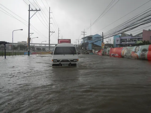 The image shows a van driving through a flooded street in the middle of a city. On either side of...