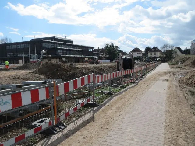 The image shows a construction site with a red and white striped barrier on the side of a road,...