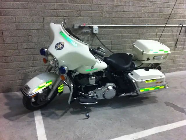 The image shows a police motorcycle parked in a parking garage next to a brick wall. The motorcycle...