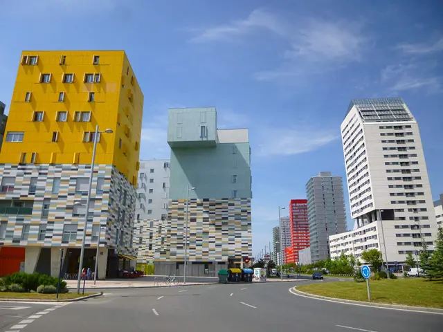 The image shows a city street with tall buildings in the background, street poles, street lights,...