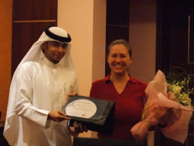 The image shows a man and woman standing next to each other, both holding a certificate and a...