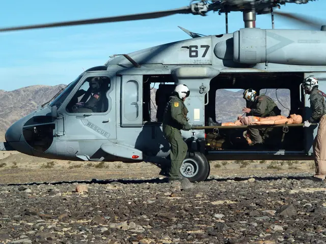 The image shows a helicopter with a man being loaded into the back of it, surrounded by people...