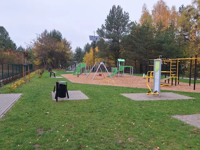 The image shows a park with a variety of playground equipment, including swings, poles, and a trash...