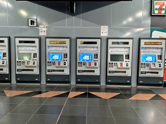 The image shows a row of ATM machines sitting on top of a tiled floor, with a wall in the...