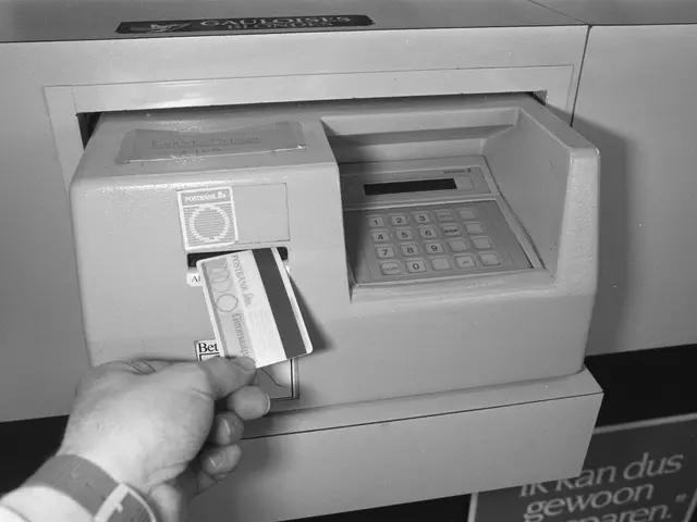 The image shows a person inserting a card into an ATM machine. The person's hand is visible,...