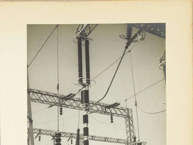 The image shows an old black and white photo of an electrical substation, with transformers and...
